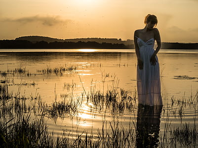 woman with white sweetheart neckline dress standing near grasses thumbnail