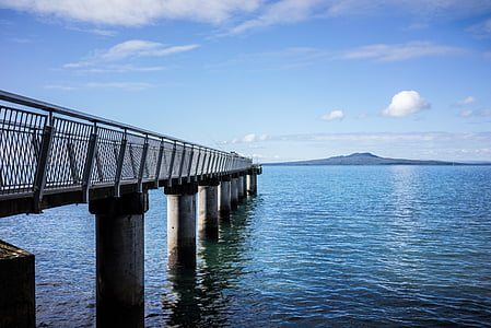narrow gray concrete dock under white and blue sky thumbnail