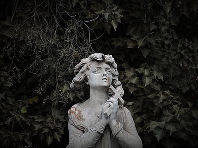 woman holding cross statue near tree thumbnail