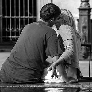 grayscale photography of man and woman sitting near building thumbnail