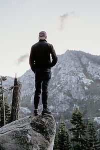 man standing on rock in front of mountain view thumbnail