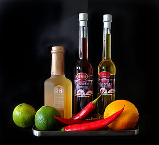 two chili peppers and limes near glass bottles thumbnail