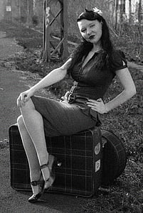 grayscale photography of woman wearing mini dress sitting on luggage thumbnail