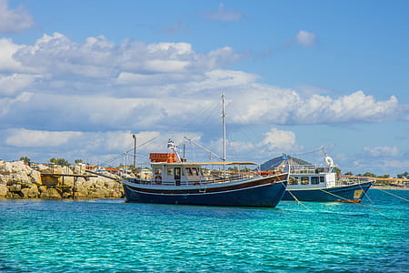 two blue boats near rocks thumbnail
