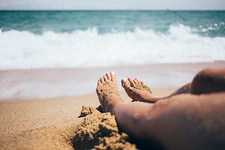 Sandy feet on the beach with waves and horizon in the background thumbnail