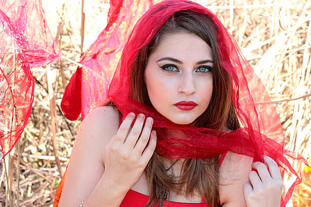 woman with makeup wearing red spaghetti strap dress and veil taking picture during daytime thumbnail