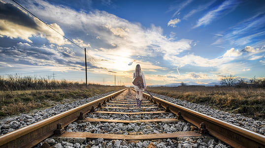 woman wearing white dress holding guitar walking on brown steel train rail road thumbnail