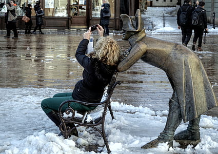 woman sitting on chair taking selfie on bending statue thumbnail