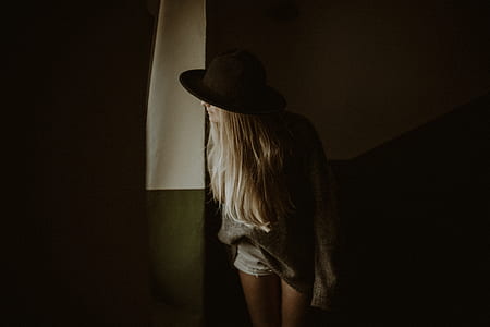 low light photography of woman wearing black hat thumbnail