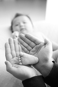 selective focus grayscale photography of baby's right foot on person's hands thumbnail