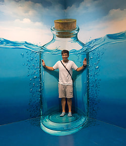 man standing on blue bottle wall painting thumbnail