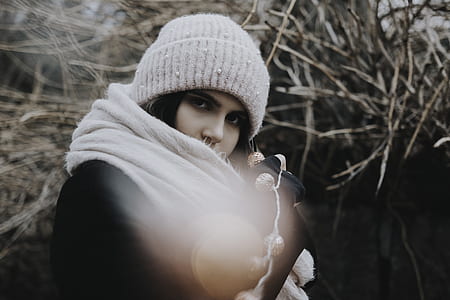 woman in white knit hat and scarf standing near tree branches thumbnail