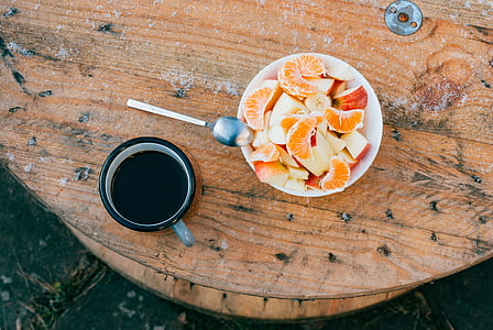 sliced fruits on bowl near cup of coffee on brown wooden table thumbnail