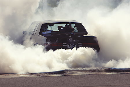 black coupe releasing white smoke on ground at daytime thumbnail