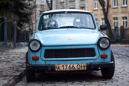 Classic Blue Car Parked Near Fence and Trees thumbnail