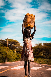girl carrying yellow plastic container on pave road thumbnail