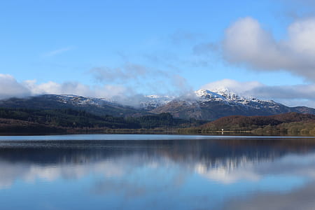 Lake Near Green Trees With Overlooking Mountain Peaks thumbnail