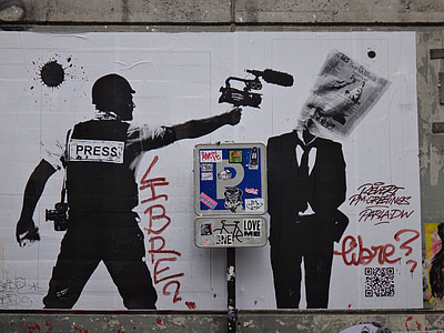 graffiti of man holding camera pointing to man in black suit jacket thumbnail