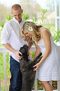 woman wearing white spaghetti-strap mini dress holding dog beside man wearing white button-up long-sleeved collared shirt thumbnail