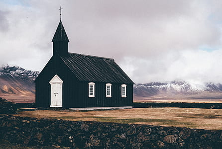 green and white chapel in middle of field at distance to snow capped mountains thumbnail
