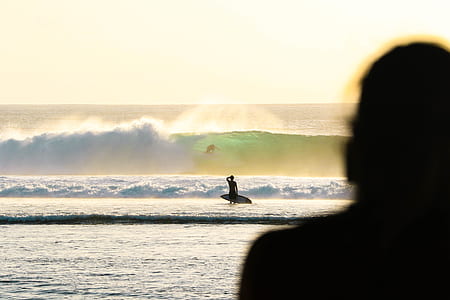 silhouette of man holding surfboard near sea waves during daytime thumbnail
