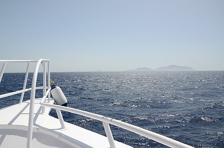 white boat with island at distance thumbnail