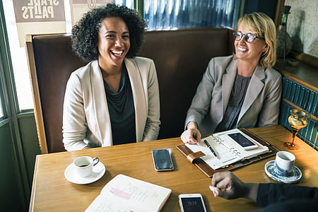 two woman sitting on brown chair inside cafe thumbnail