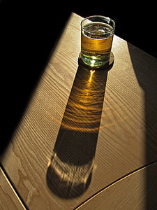 rocks glass filled with liquor spotted by light thumbnail