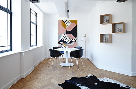 round white pedestal table with four black chairs on brown surface thumbnail