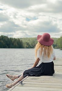 woman sitting on brown wooden dock along body of water thumbnail