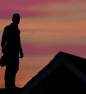 silhouette photo of man standing on roof thumbnail