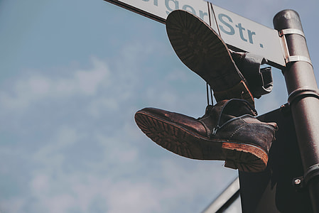 pair of brown leather shoes hanging on street sign during daytime thumbnail