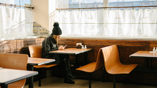 woman using smartphone sitting at desk near window thumbnail