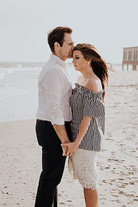 man kissing the head of woman on seashore during daytime thumbnail
