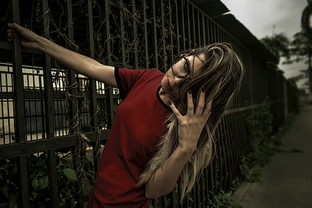 woman in red crew-neck t-shirt black metal gate thumbnail