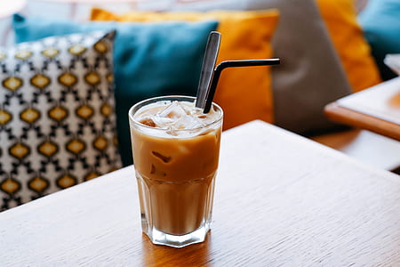 clear drinking glass filled with iced coffee on brown wooden table thumbnail