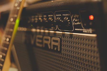 selective focus photography of black Rivera guitar amplifier with leaning brown guitar thumbnail