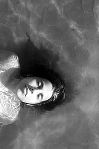 grayscale photo of woman lying on water thumbnail