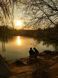 two people sitting on bench facing body of water thumbnail