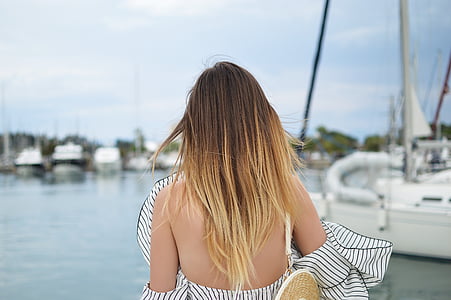 woman in white and black stripe off-shoulder blouse standing on docking pier near speed boat thumbnail