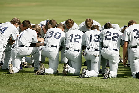 Baseball Player Kneeling on Grass Field during Daytime thumbnail