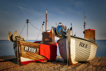 two brown and white wooden boats on brown sand near body of water at daytime thumbnail