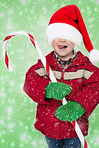boy in red jacket, red Santa hat and green gloves holding large candy cane thumbnail