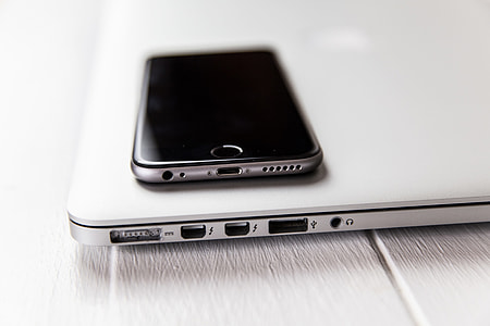 Closeup shot of laptop computer and iPhone mobile smartphone on a white desk thumbnail