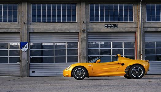 Yellow Coupe Parked Near Brown Painted Warehouse thumbnail