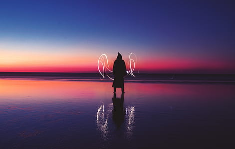 person standing on seashore during nighttime thumbnail
