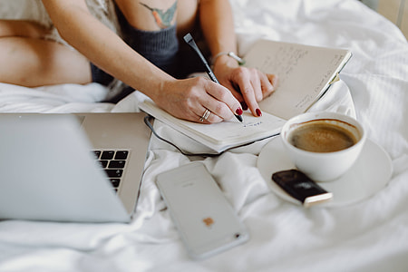 Woman working on a laptop while enjoying a breakfast coffee and chocolate in bed thumbnail