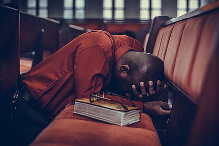 man holding his head down on bench and eyeglasses on top of book thumbnail