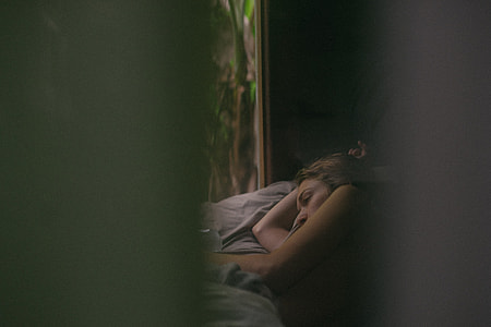 person lying on gray bed in room thumbnail