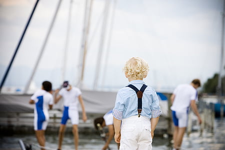 blonde boy wearing blue shirt standing near body of water thumbnail